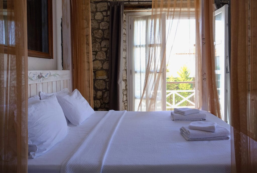 Bright boutique bedroom with soft curtains and natural stone wall, representing the warm and inviting guest experience showcased through professional Airbnb websites.