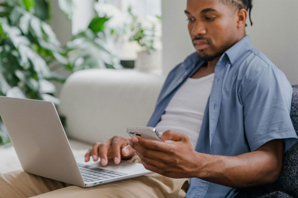 Guest comparing Airbnb listings on phone and laptop before booking decision