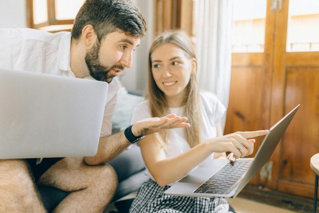 Couple comparing Airbnb listings on laptop while discussing travel options