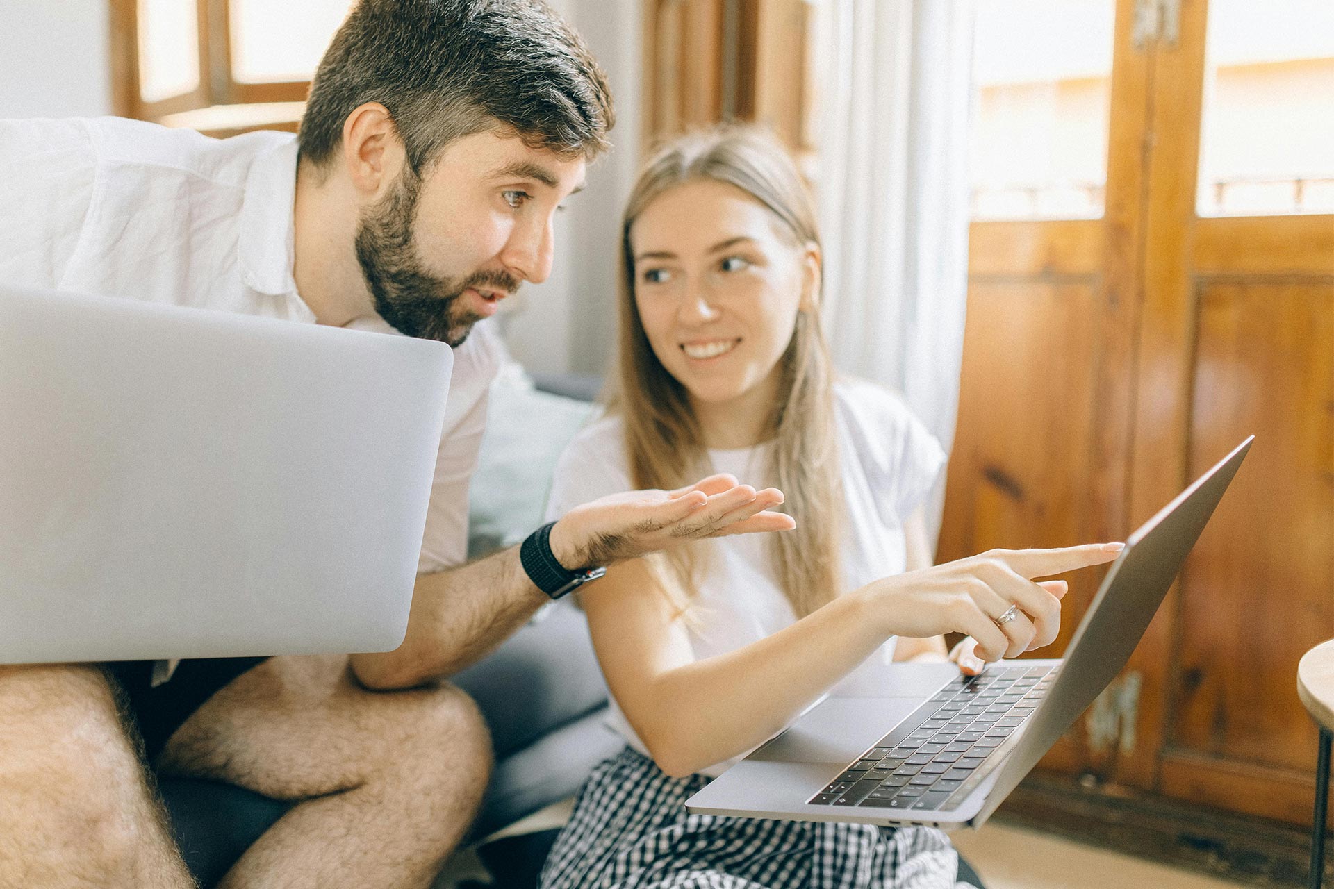 Couple comparing Airbnb listings on laptop while discussing travel options