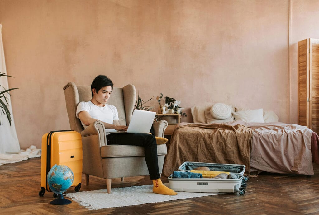 Traveler sitting in a cozy vacation rental room using a laptop to research or book their stay, representing how guests search for Puerto Rico Airbnbs online.