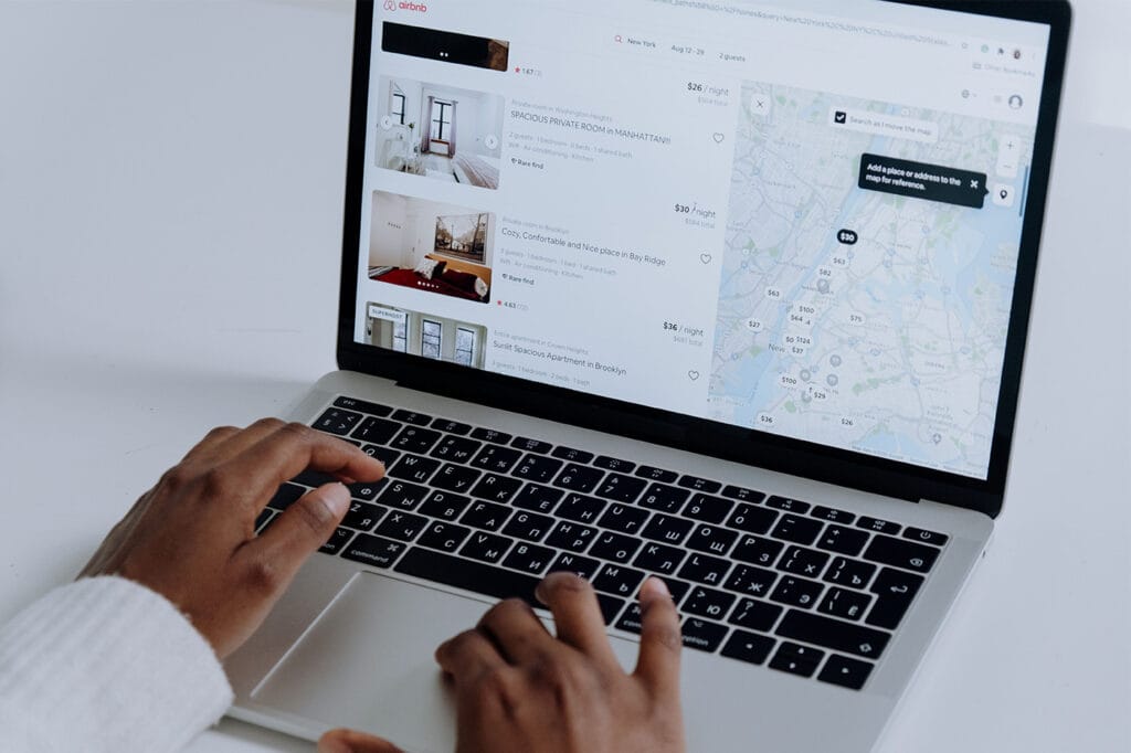 Host browsing Airbnb search results on a laptop while optimizing a vacation rental listing for better visibility and more bookings.