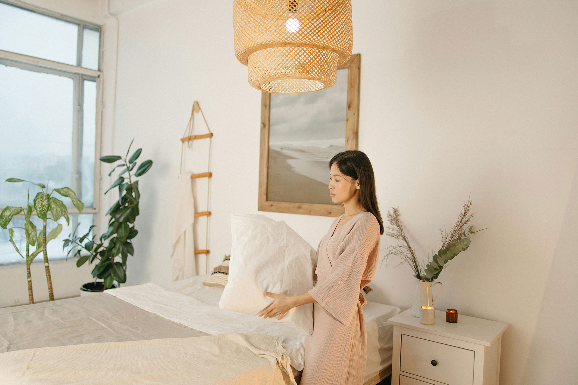 Host preparing a stylish vacation rental bedroom with natural light and cozy interior design