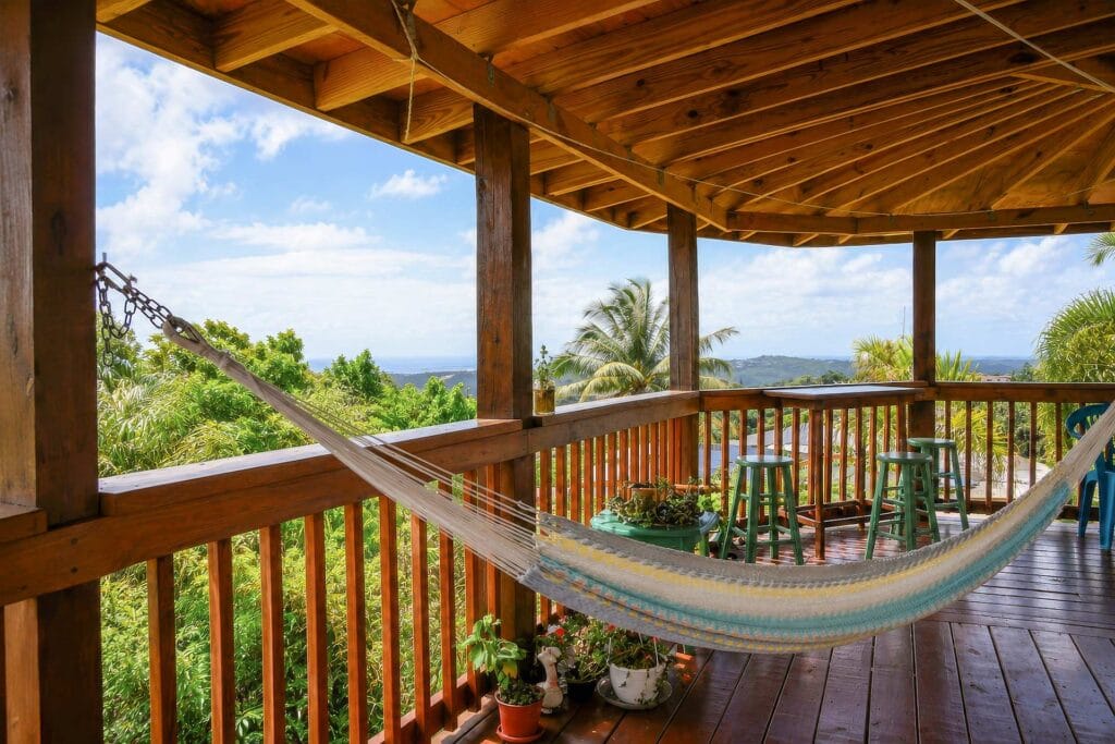 Covered terrace with hammock and mountain views at El Chalet in Puerto Rico, highlighting the relaxing outdoor experience and natural surroundings.