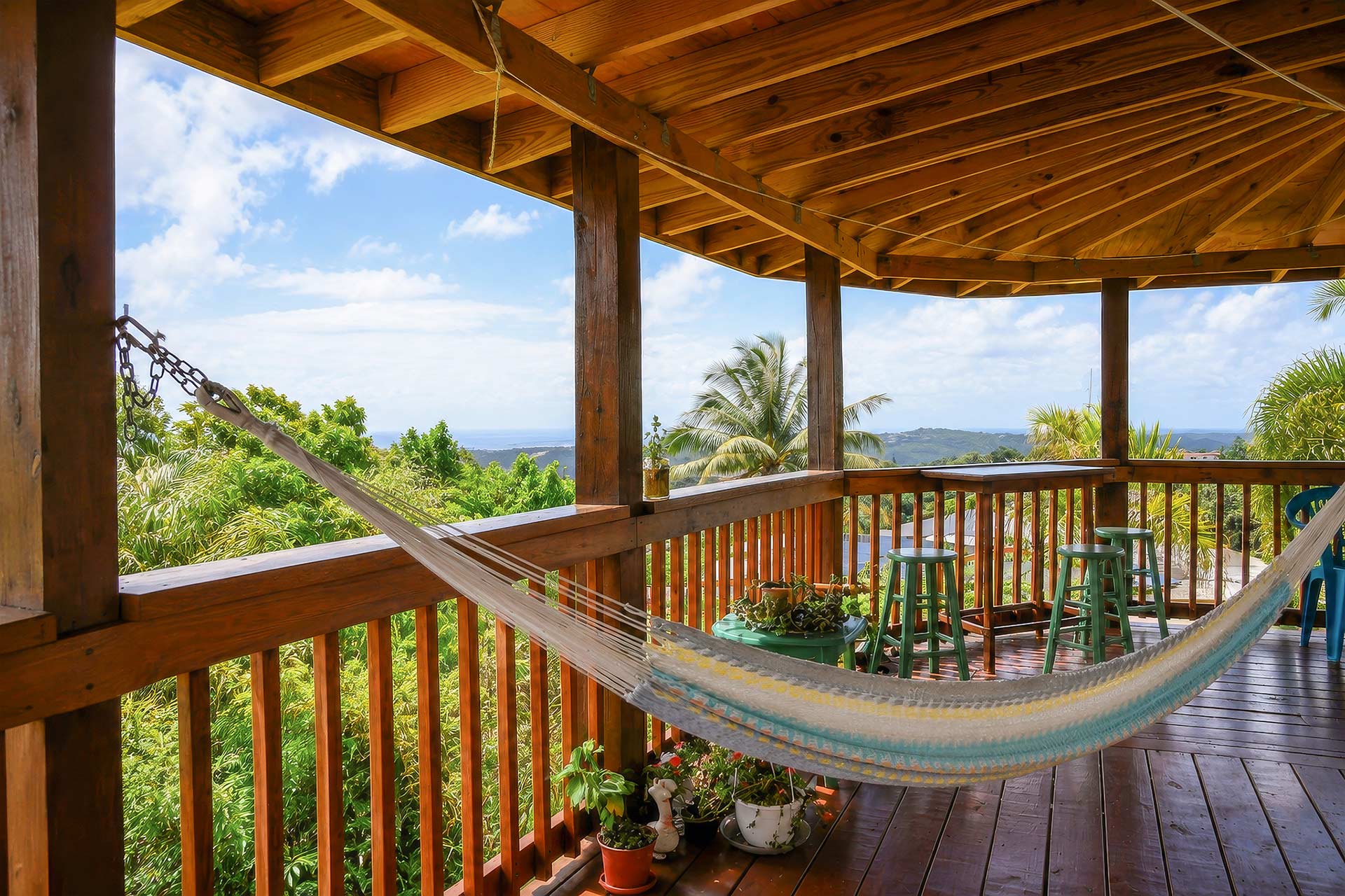 Covered terrace with hammock and mountain views at El Chalet in Puerto Rico, highlighting the relaxing outdoor experience and natural surroundings.