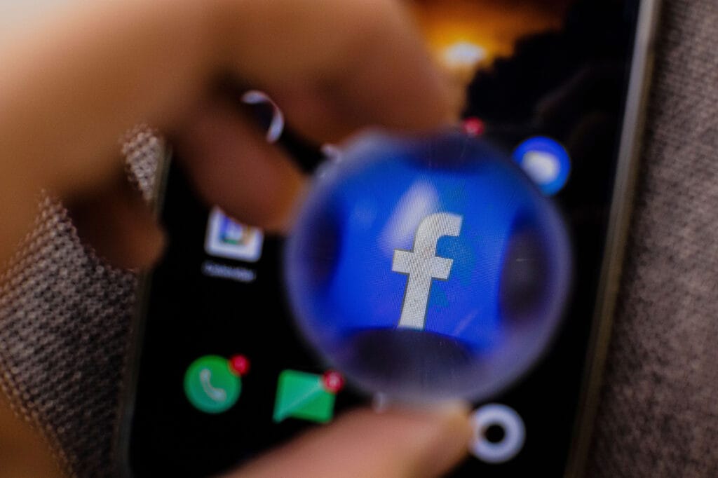 Close-up of a smartphone with the Facebook app highlighted, illustrating social media advertising for vacation rentals and the importance of directing paid traffic to a host’s own website instead of relying solely on booking platforms.