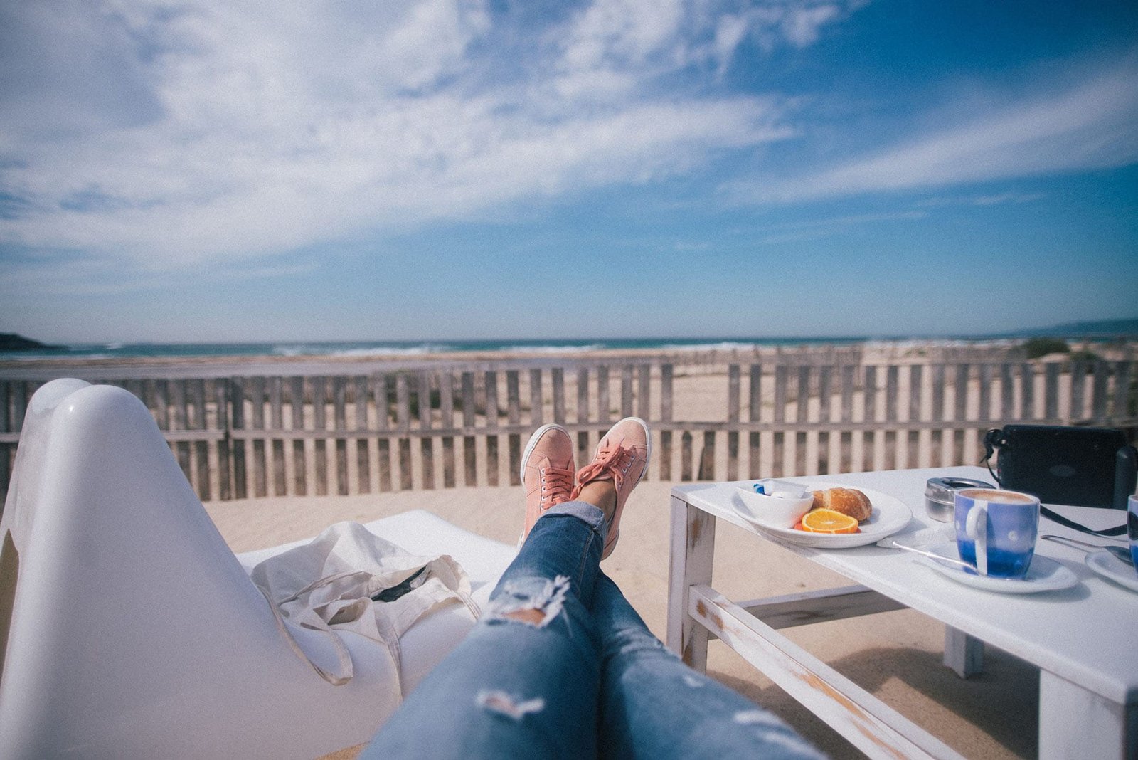 Guest relaxing with morning coffee and breakfast overlooking the beach at a vacation rental