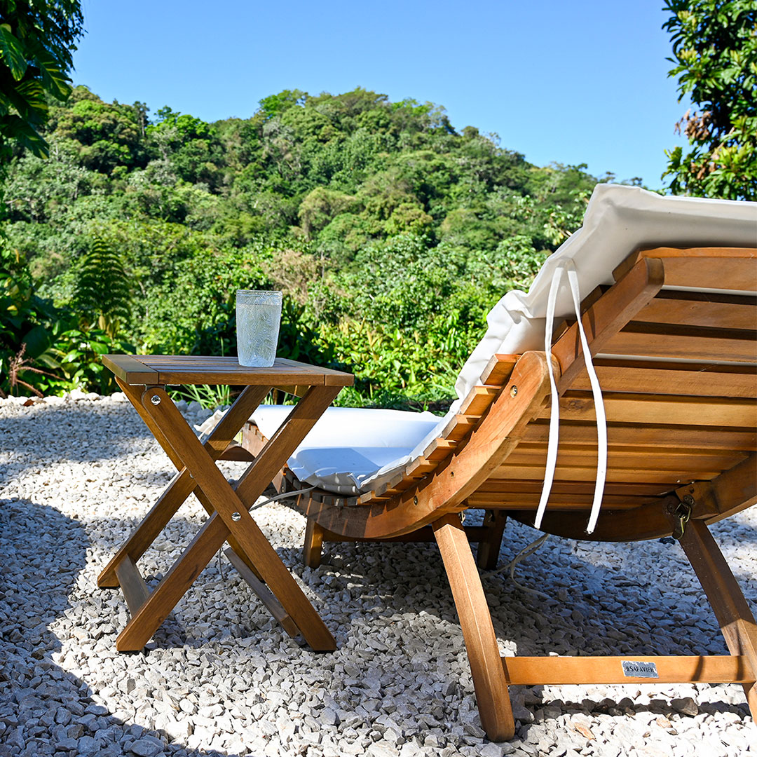 Outdoor lounge chair with a cold drink overlooking lush tropical mountains, representing a relaxing and high-quality Airbnb guest experience in Puerto Rico.