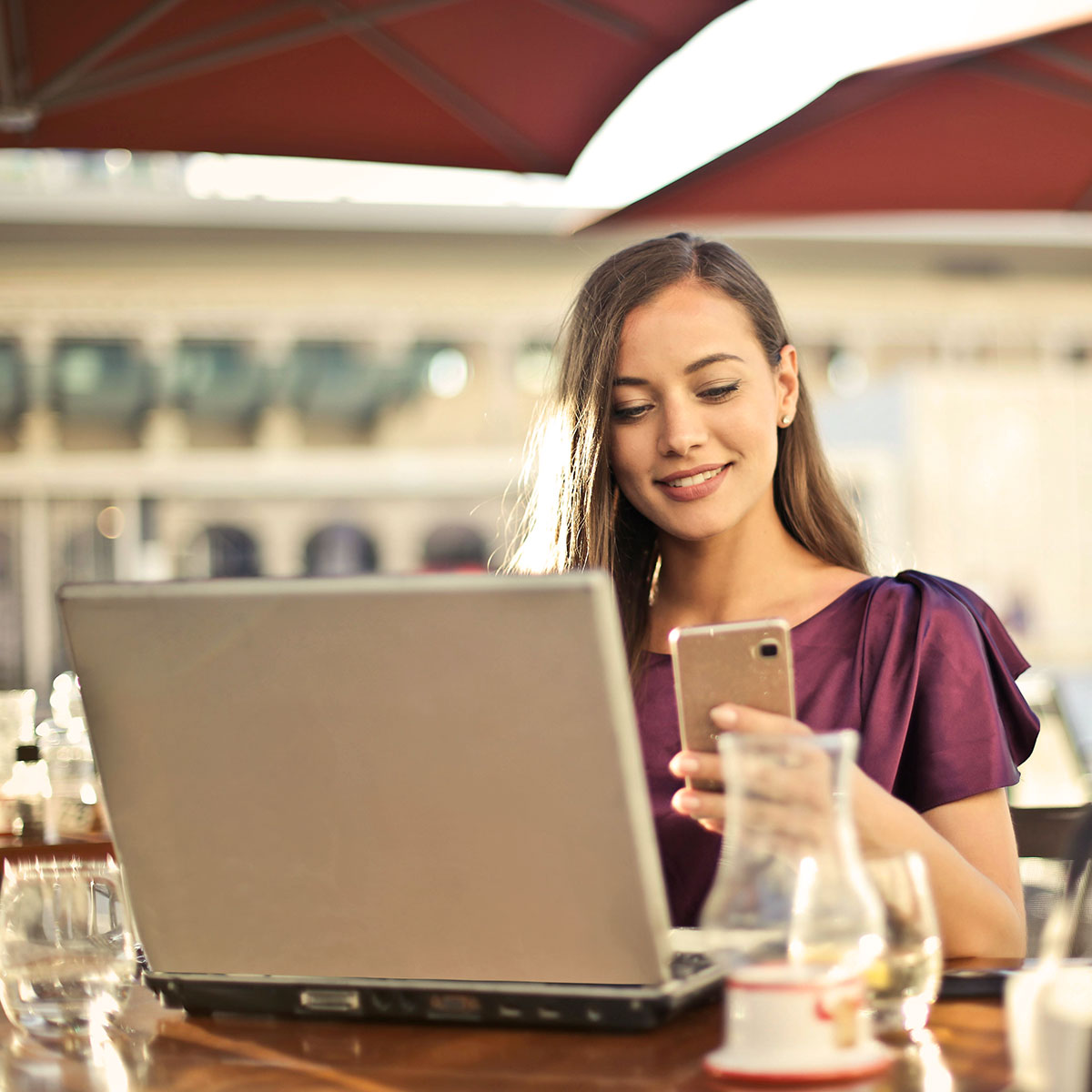 Woman smiling while checking online sales or reviews on her laptop and smartphone.